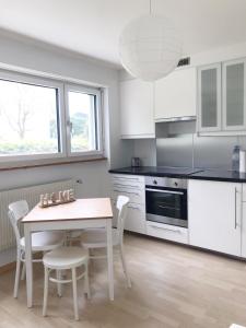 una cucina con armadi bianchi, tavolo e sedie di GreenPlace City Apartment a Berna