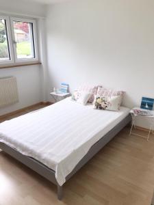 una camera da letto con un grande letto con lenzuola bianche di GreenPlace City Apartment a Berna