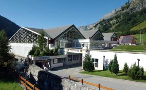 un grande edificio bianco con montagne sullo sfondo di Campingplatz mit Restaurant & Sportarena Leukerbad a Leukerbad