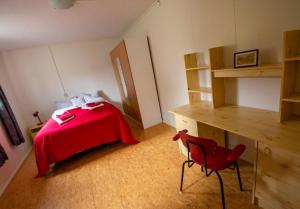 Saurbær Apartment في فارماهليد: غرفة نوم بسرير احمر وكرسي احمر