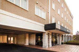 a large brick building with a parking lot at TsukubaNoYu Urban Hotel in Tsukuba