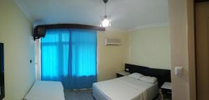 a bedroom with two beds and a blue curtain at Delphin Apart Hotel in Side