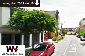 una macchina rossa parcheggiata in una strada accanto a un albero di White Hope Apartment a Lima