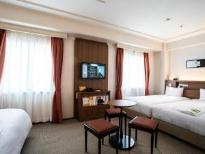 Hotel New Hankyu Osaka Annex في أوساكا: غرفة فندقية بسريرين وطاولة