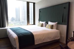 a bedroom with a large bed with a large window at THE KNOT TOKYO Shinjuku in Tokyo