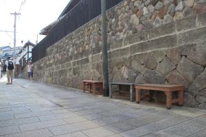 two benches on a sidewalk next to a stone wall at Beppu Kannawa Onsen HIROMIYA in Beppu