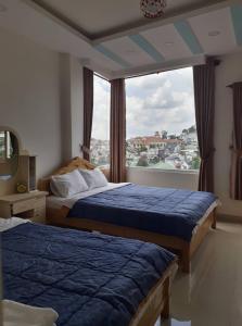 a bedroom with two beds and a large window at Cam Ly Homestay in Da Lat