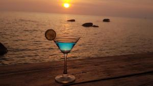a glass of wine sitting on a table near the ocean at Free Beach Resort in Phú Quốc