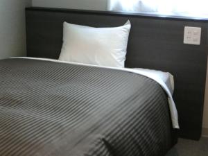 a bed with a white pillow next to a window at Orange Inn Sendaihigashi in Sendai