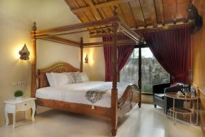 a bedroom with a canopy bed and a window at Kampoeng Joglo Boutique Hotel in Yogyakarta