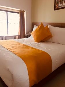 Hotel Ambala Bogota Colonial في بوغوتا: سرير بمخدات صفراء وبيضاء ونافذة