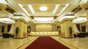 een grote feestzaal met rode vloerbedekking en zuilen bij Daniel Hill Hotel in Tasjkent