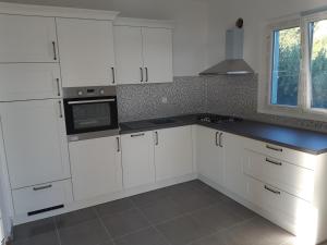 a white kitchen with white cabinets and a window at Jelena Holiday House in Karlobag