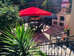 a patio with a table and a red umbrella at Mandarin in Makhinjauri