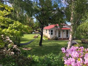 a house with a hammock in a yard with flowers at Tailor Made Tekapo Accommodation - Hostel in Lake Tekapo