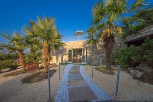 a stone house with palm trees in front of it at Garda Hill Boutique Apartments with Panoramic Pools e Agriturismo in Soiano del Lago