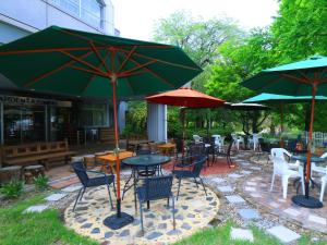 a patio with tables and chairs and umbrellas at Guestroom Garden Azumino in Azumino