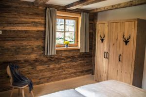 a bedroom with wooden walls and a bed and a window at Tauernwelt-Das AlpenNatur Chalet in Bruck an der Großglocknerstraße