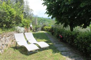a pair of white chairs sitting in a garden at Podere I Rovai-apt IL RIFUGIO- in the heart of Tuscany in Reggello