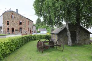 an old cart sitting in the grass next to a building at Gîte de la Lavandière à Ucimont in Ucimont