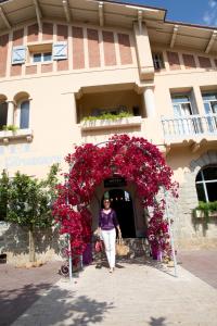 a woman walking under an arch of red flowers at Le Mas des Citronniers in Collioure