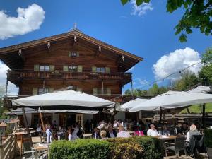 a group of people sitting at tables in front of a building at Landhotel Vordergrub in Kitzbühel