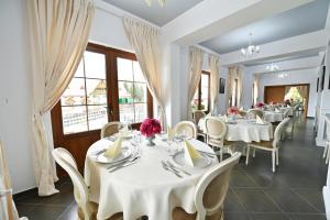 a restaurant with white tables and chairs and windows at Pensiunea Castania - Pensiune cu piscina la munte in Polovragi