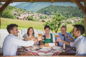 un gruppo di persone sedute intorno a un tavolo a bere vino di Garnì Lilly a San Lorenzo in Banale