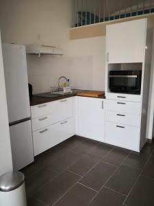 a kitchen with white cabinets and a tile floor at studio en plein centre ville à 8 minutes de l'océan in Le Porge