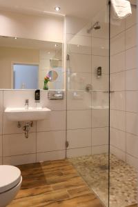 a bathroom with a shower and a sink and a toilet at Hotel Gut Moschenhof in Düsseldorf