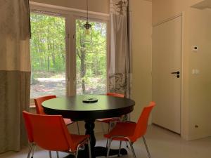 comedor con mesa, sillas y ventana en Wina Boshuisje Veluwe, en Otterlo