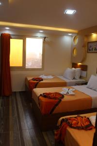 a hotel room with three beds and a window at Osiris Hotel Cairo in Cairo