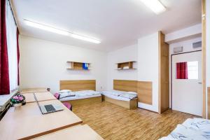 Habitación con 2 camas y escritorio con ordenador portátil. en Hostel Sinkule, en Praga