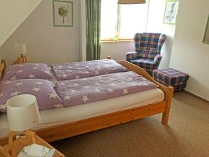 Schlafzimmer mit einem Bett mit lila Bettwäsche und einem Stuhl in der Unterkunft Ferienwohnung auf der Sonneninsel in Fehmarn