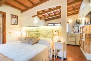 a bedroom with a white bed and a kitchen at B&B Rosso Baccara in Montevettolini