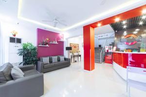 a living room with a couch and a red wall at RedDoorz Plus near SM Lanang Davao in Davao City