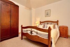 1 dormitorio con cama de madera y armario de madera en Shearwater Self Catering en Union Hall