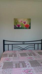 a bed with a picture of flowers on the wall at Ground beach studio in Nea Potidaea