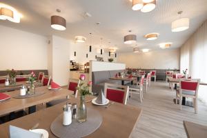 里德林根的住宿－Hotel Gudrun，餐厅设有木桌和红色椅子