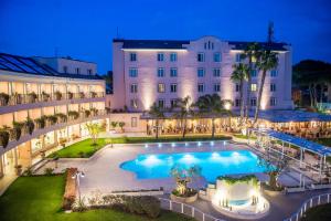 an exterior view of a hotel with a large pool at Hotel Isola Sacra Rome Airport in Fiumicino
