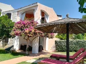 a house with a bunch of flowers and an umbrella at Villa La Minda with a stunning view in Badesi