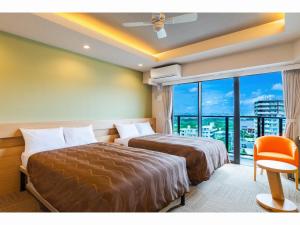 Habitación de hotel con 2 camas y ventana grande. en Yenns Marina Inn Mercy en Ginowan
