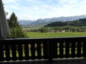 uma varanda com vista para um campo verde e para as montanhas em Landhaus Kogel em Ofterschwang