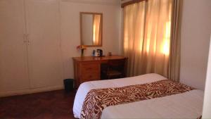 a bedroom with a bed and a dresser and a mirror at ACK St.Julians Centre in Limuru
