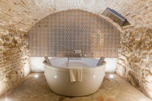 a bathroom with a bath tub in a brick wall at Hotel Pintor El Greco in Toledo