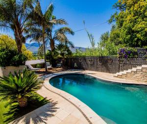 a swimming pool in a yard with palm trees at Ladera - Vista Self-catering Guesthouse in Paarl