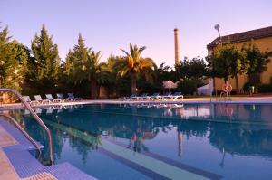 a large swimming pool with chairs and a factory at Hotel El Carmen in Puente-Genil