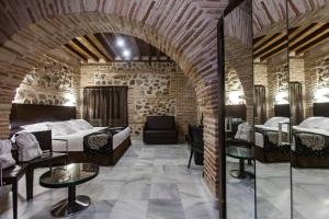 um quarto de hotel com duas camas numa parede de tijolos em Hotel Pintor El Greco em Toledo