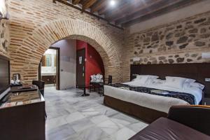 a bedroom with a large bed and a brick wall at Pintor El Greco in Toledo