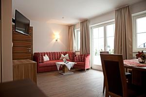 a living room with a red couch and a table at Villa Sepp in Ramsau im Zillertal